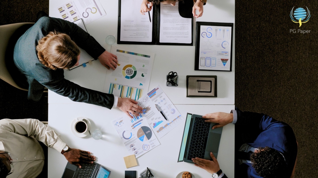 Collaborative workspace with mutiple people discussing forecasting documents with data in an office setting.